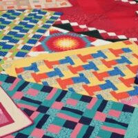 A patchwork of brightly coloured quilts fill the frame