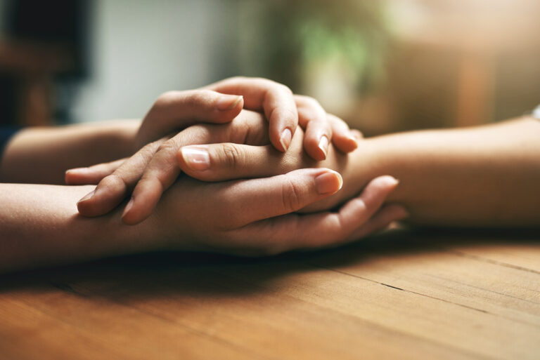 Women holding hands for support, hope, comfort and compassion.