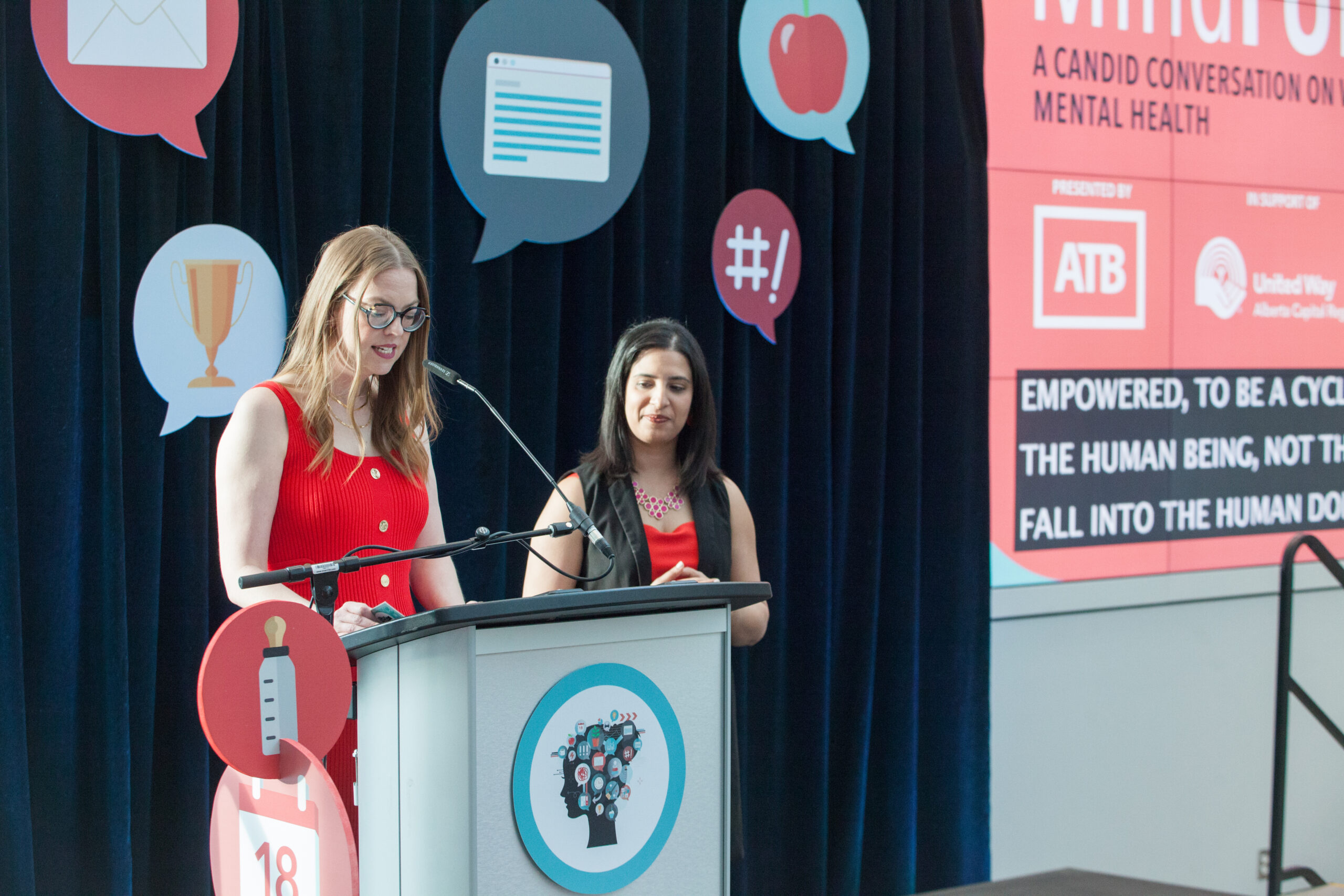 Heather MacCallum speaks at a podium, addressing an audience.